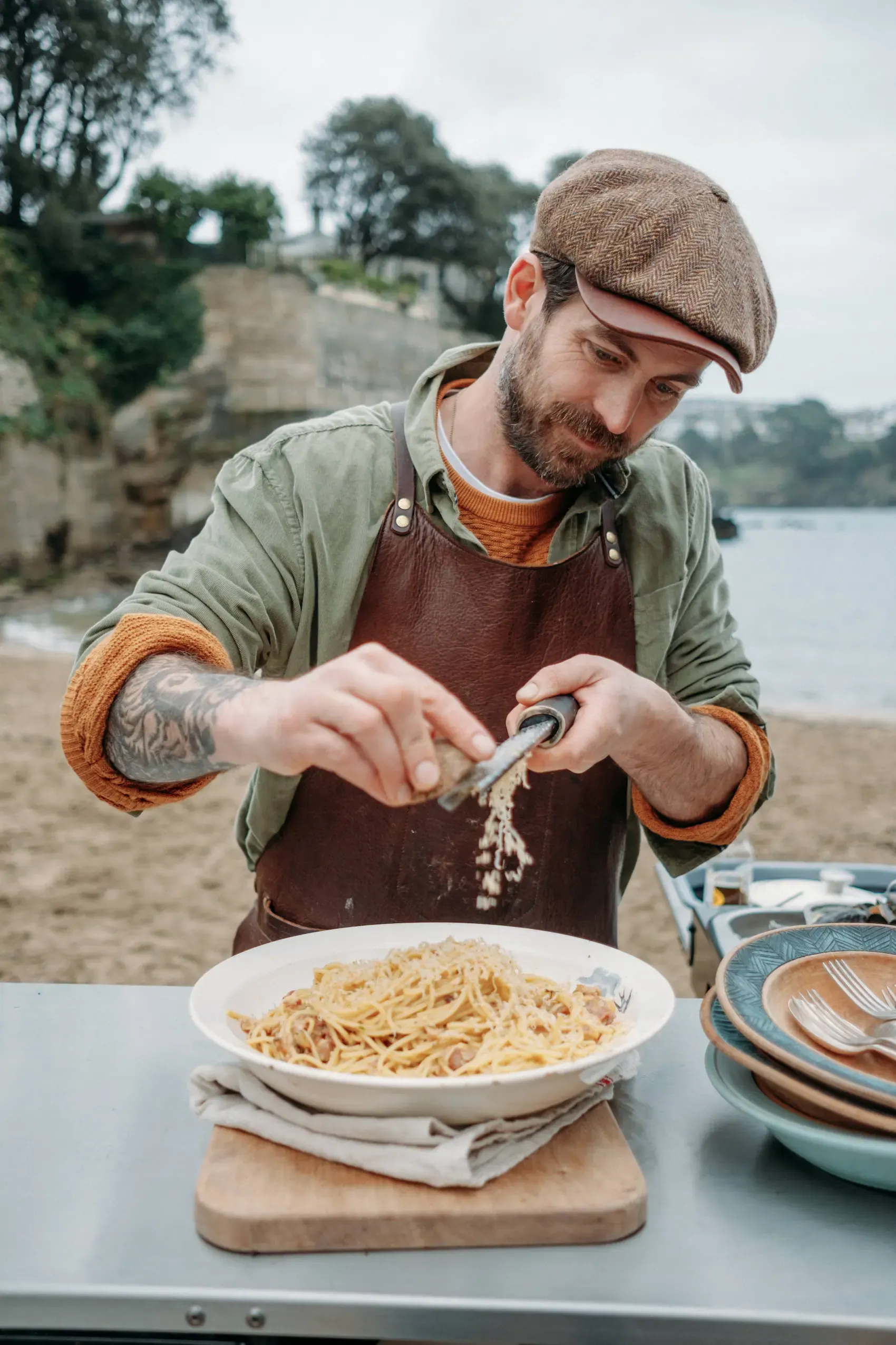 James Strawbridge grating Cornish cheese over a carbonara on the mobile kitchen at Readymoney Beach, Fowey, Cornwall