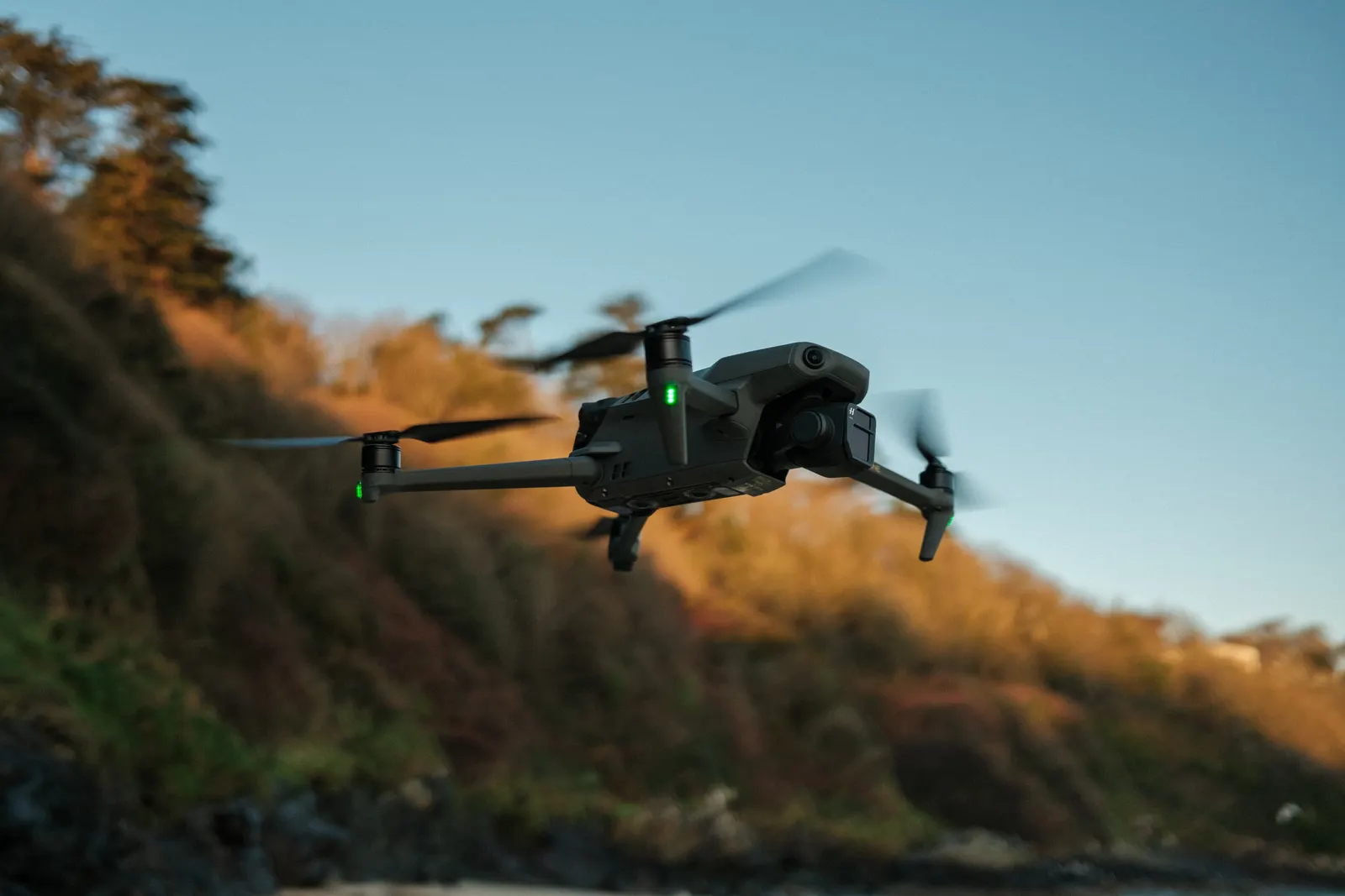A camera drone flying above a wooded landscape