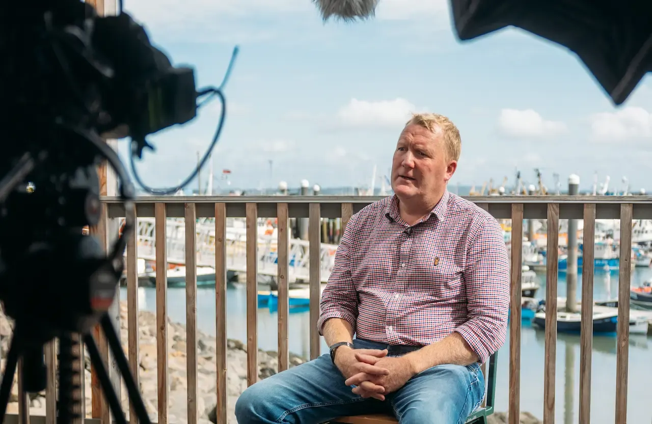 On-camera interview at Newlyn harbour for the Marine Stewardship Council, with fishing boats in the background and cinema camera and lighting visible in foreground