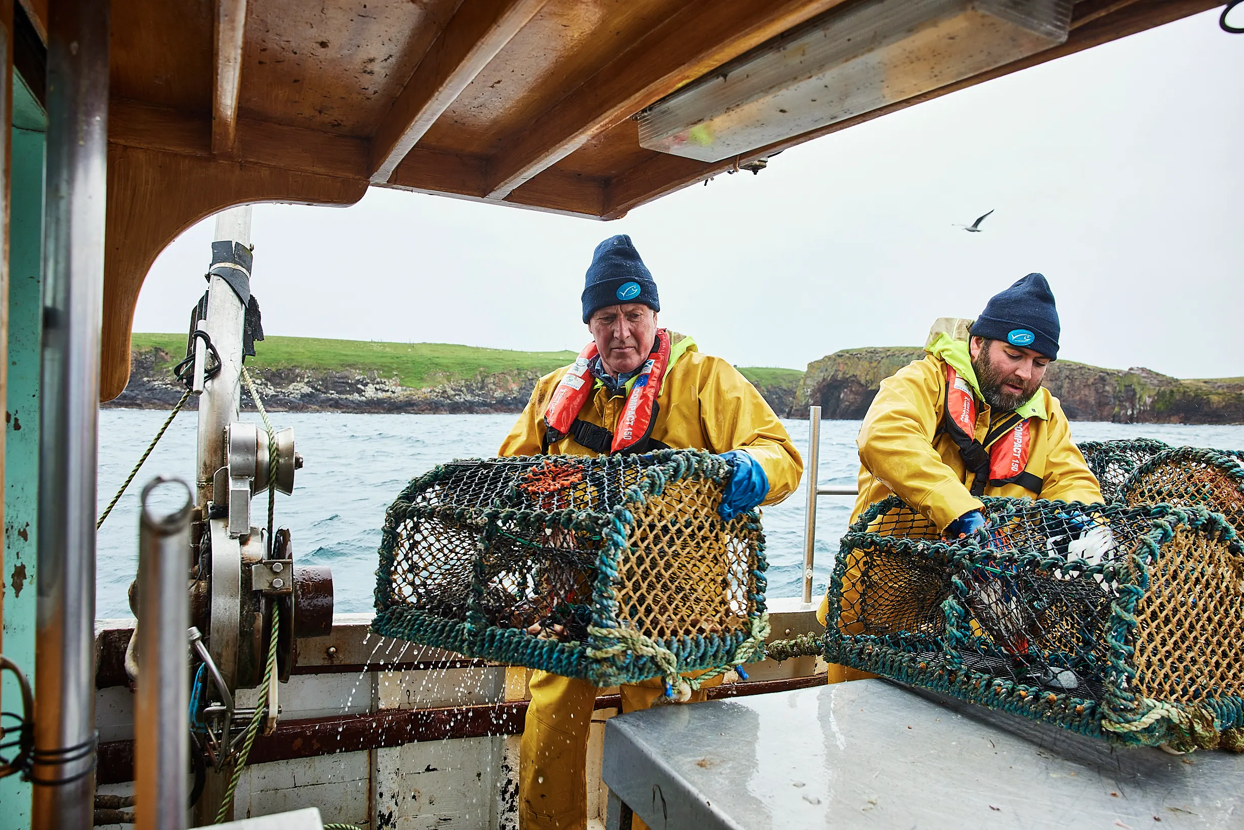 Two crab fishermen hauling pots aboard a fishing boat in Shetland, photographed by David Loftus during the All Hands On Deck campaign shoot
