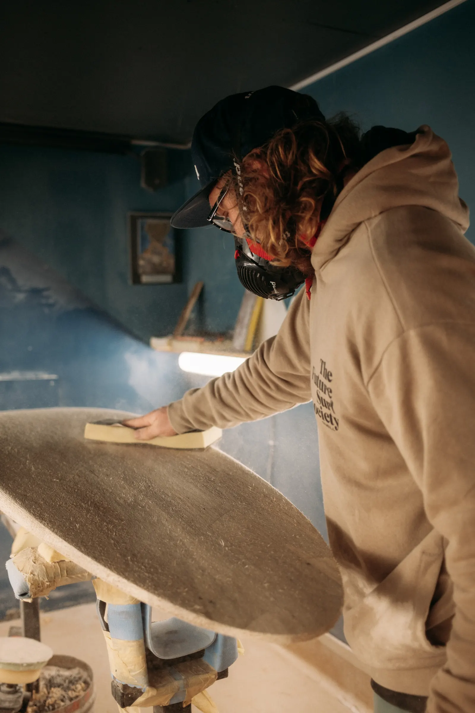 A surfboard maker sanding a board during filming for the National Maritime Museum Cornwall SURF! exhibition
