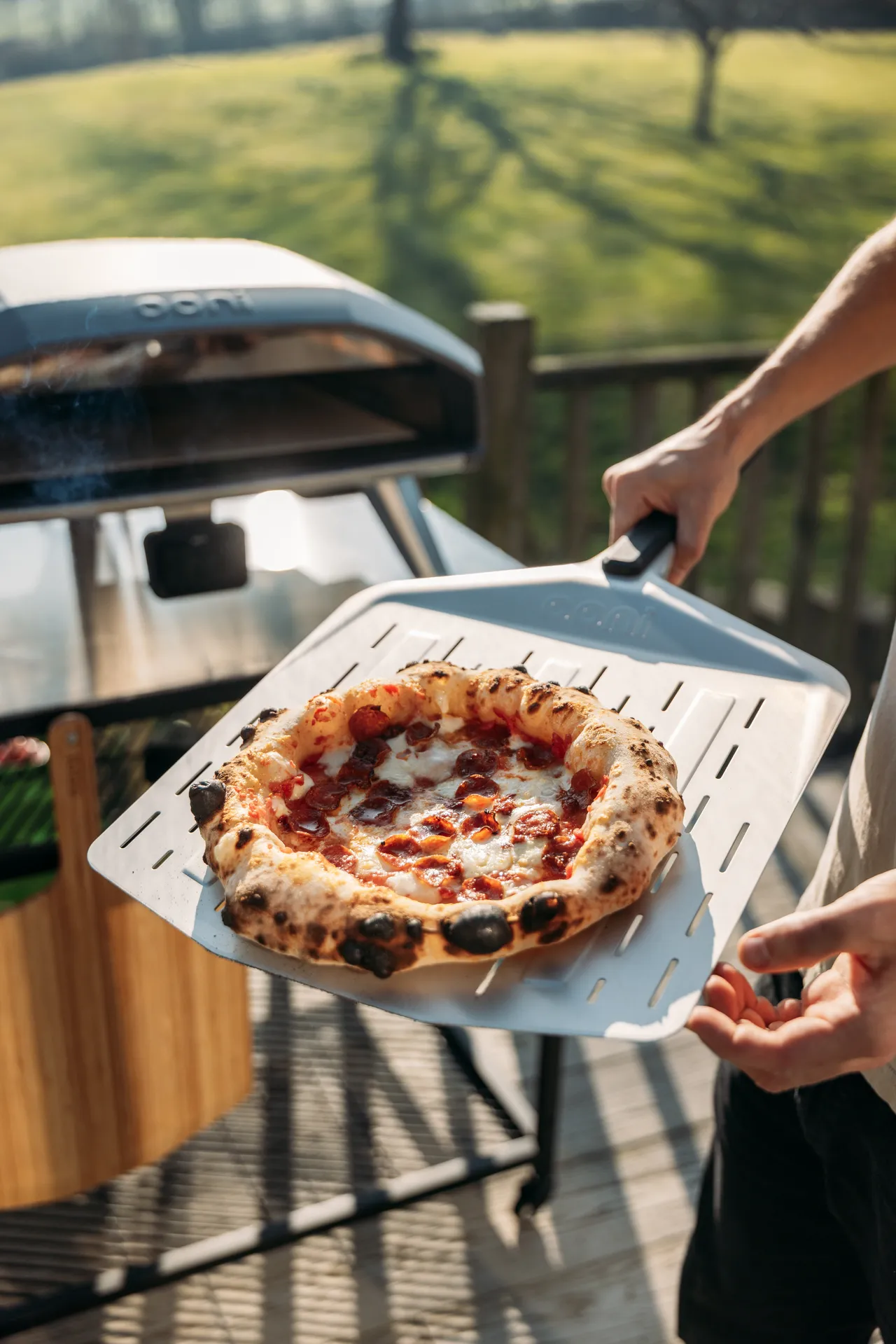 Fresh pepperoni pizza being lifted from an Ooni oven during the Ooni Cooks spring recipe series