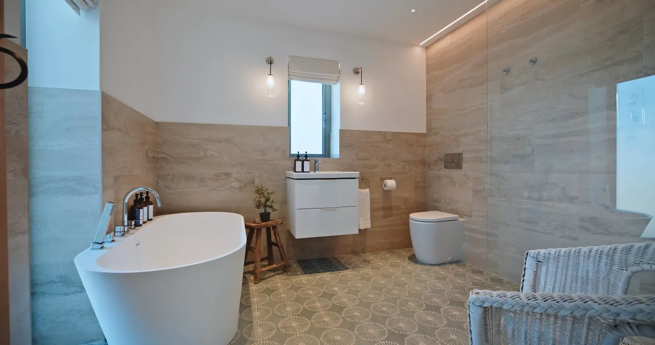 Vertical social frame from Rosevean: a freestanding bath in a stone-tiled bathroom