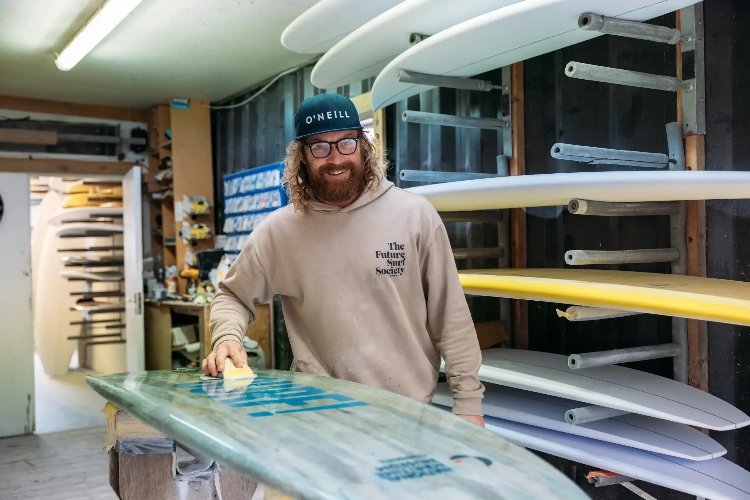 Surfboard shaper Ben Skinner polishing a board at Skindog Surfboards workshop, filmed for the National Maritime Museum Cornwall SURF exhibition